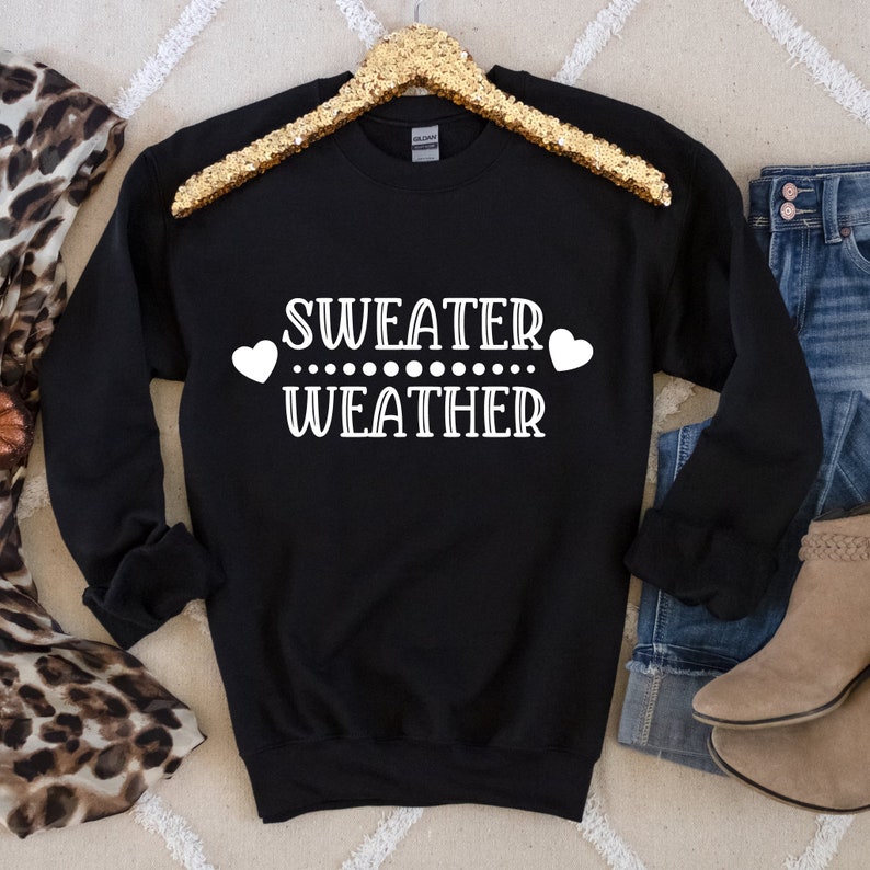 May include: Black sweatshirt with white text that reads "Sweater Weather" with two white hearts on either side of the text.