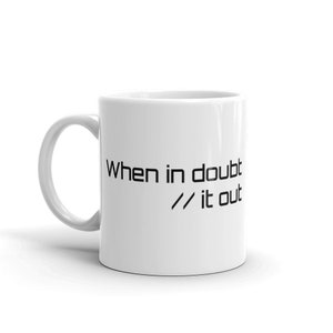 May include: White ceramic coffee mug with black text that reads "When in doubt // it out".