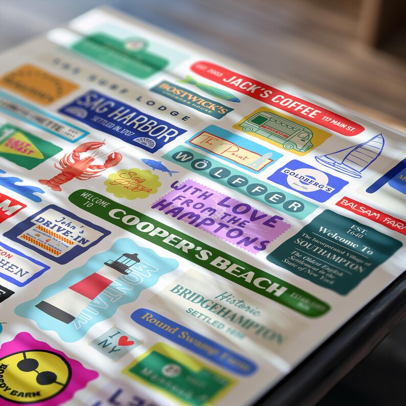 May include: A collection of colorful stickers featuring various designs and text. The stickers include images of a lobster, a sailboat, and a lighthouse, along with text such as "Jack's Coffee" and "Sag Harbor".