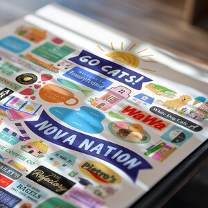 May include: A collection of colorful stickers with various designs and text, including "GO CATS!", "Welcome to Pennsylvania", "NOVA NATION", and "White Dog Cafe". The stickers feature illustrations of food, buildings, and a sun.