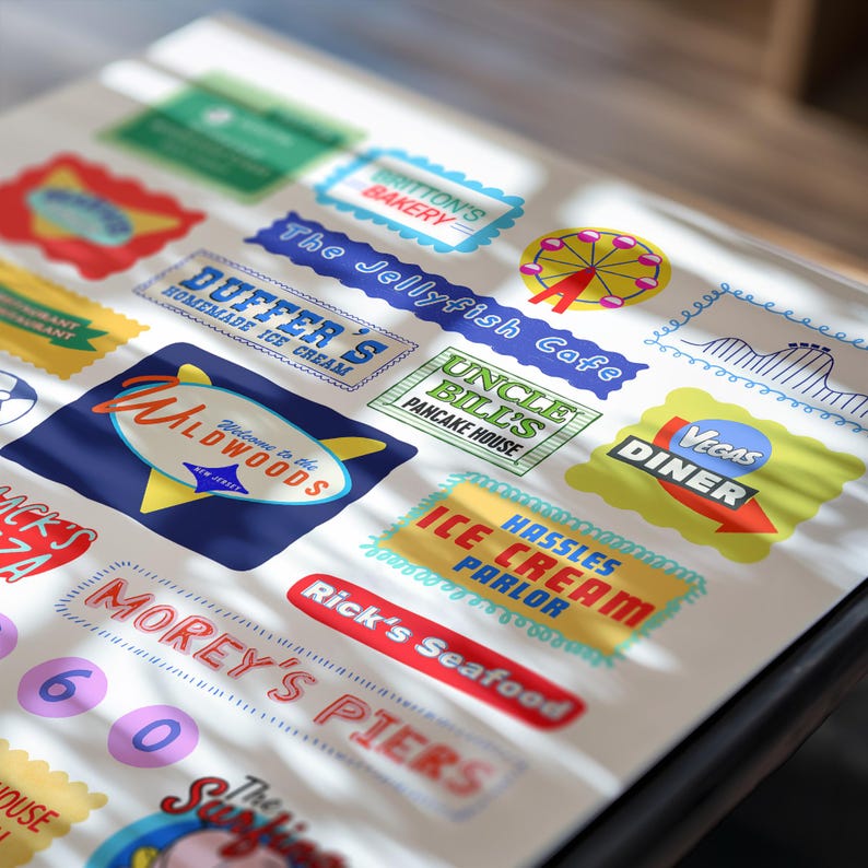 Peut inclure: Une collection d'autocollants color&eacute;s de style vintage repr&eacute;sentant diverses entreprises. Les autocollants incluent du texte tel que "Wildwoods", "Duffer's Homemade Ice Cream" et "Vegas Diner". Les motifs utilisent des polices r&eacute;tro et des couleurs vives, &eacute;voquant la nostalgie.