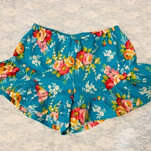May include: Blue floral print shorts with a ruffled hem. The shorts have a high waist and a relaxed fit.