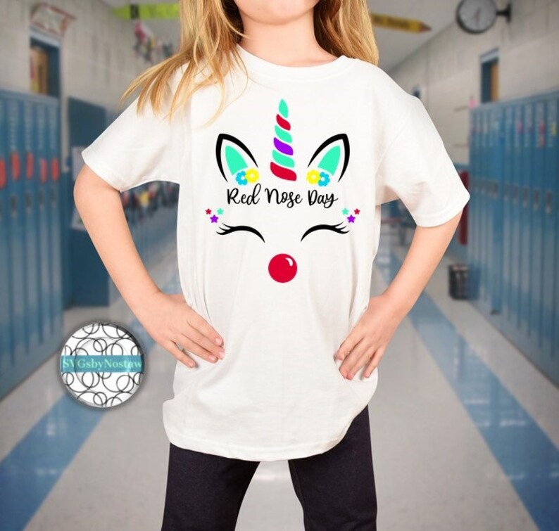Pu&ograve; includere: Maglietta bianca con un design di unicorno con un naso rosso e il testo "Red Nose Day".