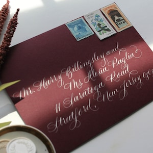 Flat Lay Calligraphy keepsake envelope with vintage stamps, wax seal and floral sprig for weddings and photoshoots
