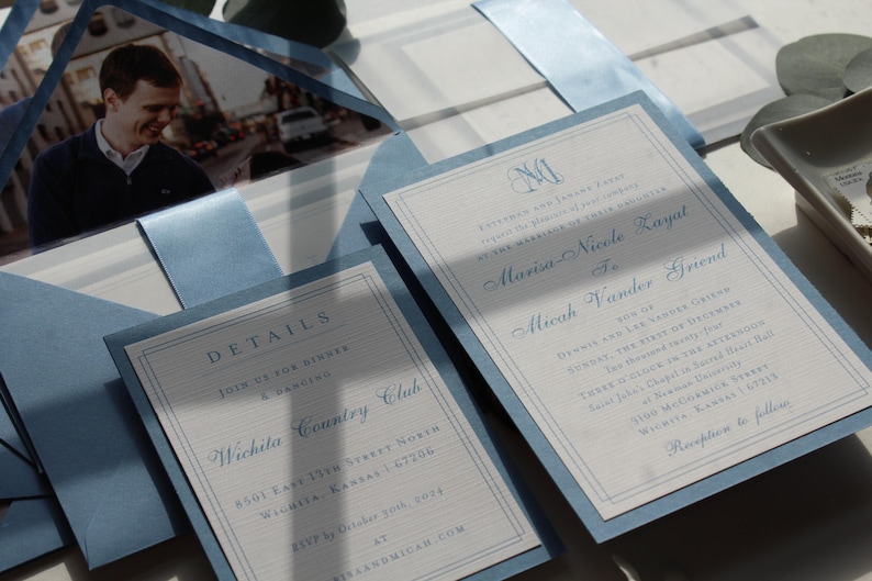 May include: Elegant wedding invitations in light blue and white. The invitations feature a photo, details, and names in a classic font. The design includes a monogram and the text "DETAILS" and "Wichita Country Club".
