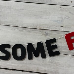 May include: A black and red banner with the words "SOME FUN" strung on white twine.