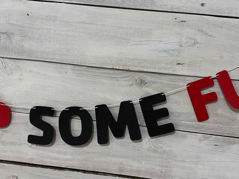 May include: A black and red banner with the words "SOME FUN" strung on white twine.