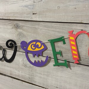 May include: Halloween banner with the word "Halloween" spelled out in colorful paper letters. The letters are decorated with a pumpkin, a ghost, a candy cane, and a swirl.