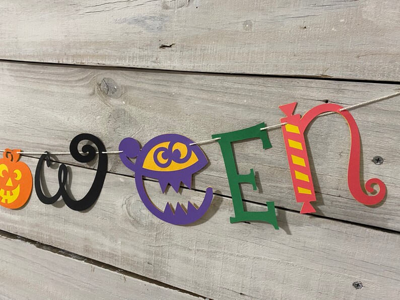 May include: Halloween banner with the word "Halloween" spelled out in colorful paper letters. The letters are decorated with a pumpkin, a ghost, a candy cane, and a swirl.