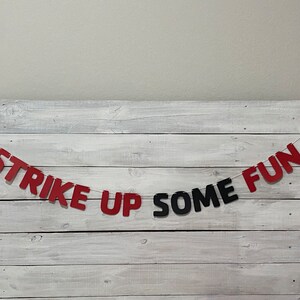 May include: Red and black paper banner with the text "Strike Up Some Fun" and bowling pin and ball cutouts on each end.