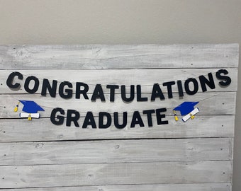 May include: Black and white banner with the text "Congratulations Graduate" with a blue graduation cap and diploma on each side.