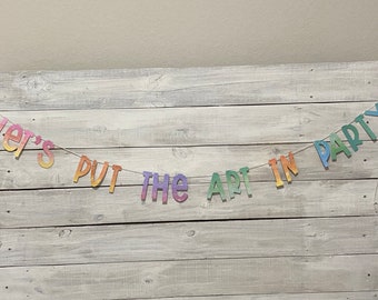 以下が含まれることがあります： 「Let's Put the Art in Party」というテキストが書かれた虹色のバナーです。