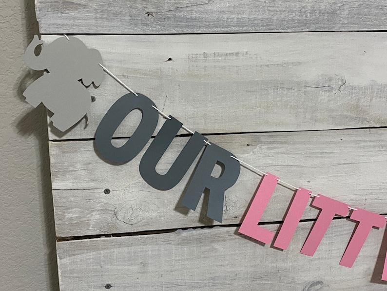 May include: A gray elephant cutout with a pink and gray banner that reads "OUR LITTLE".