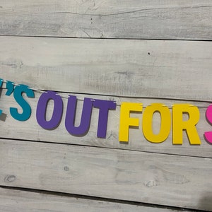May include: A colourful paper banner with the text "School's Out For Summer" in blue, purple, yellow and pink letters.
