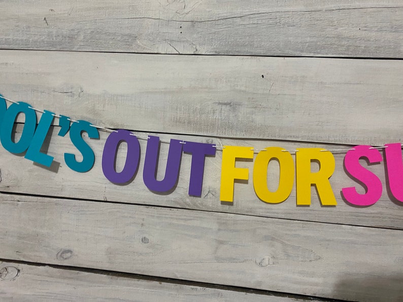 May include: A colourful paper banner with the text "School's Out For Summer" in blue, purple, yellow and pink letters.