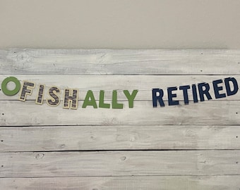Peut inclure: Une bannière avec le texte "OFISHALLY RETIRED" en lettres vertes et bleues. Les lettres sont en papier et sont enfilées sur une ficelle.