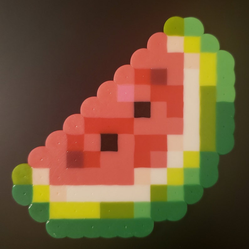 May include: A watermelon slice made of colorful beads. The watermelon is red, pink, white, and green. The rind is green.