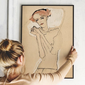 May include: A black framed print of a line drawing of a woman with red hair, wearing a white blouse, with her hands clasped in front of her.