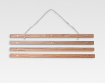 May include: A wooden poster hanger with four hanging bars and a white string for hanging. The hanger is made of natural wood and has a rustic look.
