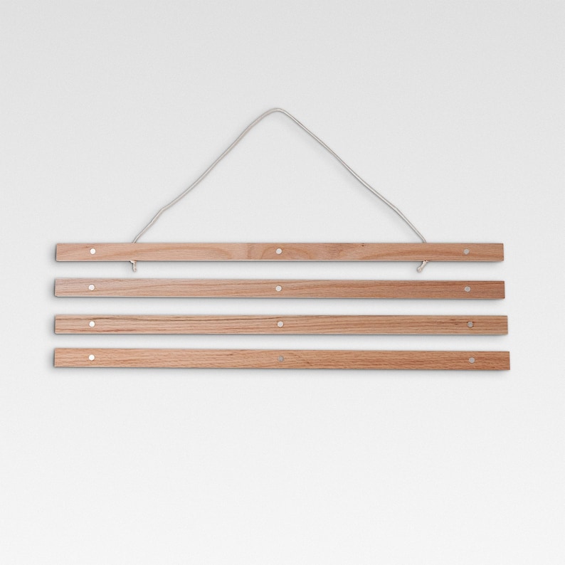 May include: A wooden poster hanger with four hanging bars and a white string for hanging. The hanger is made of natural wood and has a rustic look.