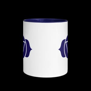 Op de afbeelding: Witte keramische mok met een donkerblauwe rand en een donkerblauw symbool van de zevende chakra aan elke kant.