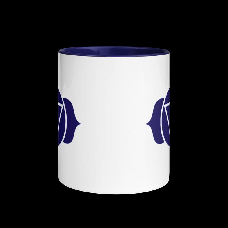 Op de afbeelding: Witte keramische mok met een donkerblauwe rand en een donkerblauw symbool van de zevende chakra aan elke kant.