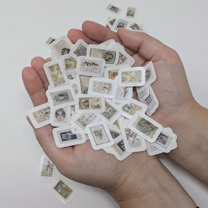 May include: A collection of small, rectangular stickers with vintage illustrations, held in open hands. The stickers feature various images in muted tones, with white borders. The overall aesthetic is antique and nostalgic.
