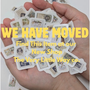 May include: A handful of small, rectangular stickers with vintage-style illustrations and text. The stickers are white with various images in muted colors. Yellow text across the image reads "WE HAVE MOVED" and directs viewers to a new shop.