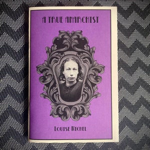 Może przedstawiać: Fioletowa książeczka z tytułem "A True Anarchist" i czarno-białym zdjęciem Louise Michel w ozdobnej ramie.