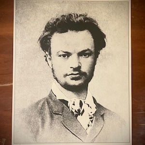 May include: Black and white portrait photograph of a man with a beard and mustache. He is wearing a suit jacket and a bow tie.