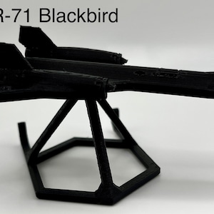 Puede incluir: Un modelo de avión SR-71 Blackbird negro en un soporte hexagonal negro.