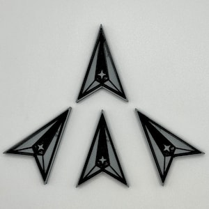 May include: Four black arrow-shaped stickers with a white star in the center. The stickers are arranged in a triangular pattern.