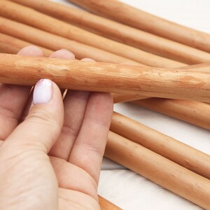 Peut inclure: Gros plan sur une main tenant un paquet de chevilles en bois lisses de couleur brun clair. Les chevilles sont dispos&eacute;es en forme de croix, les extr&eacute;mit&eacute;s des chevilles &eacute;tant visibles.