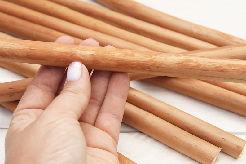 Peut inclure: Gros plan sur une main tenant un paquet de chevilles en bois lisses de couleur brun clair. Les chevilles sont dispos&eacute;es en forme de croix, les extr&eacute;mit&eacute;s des chevilles &eacute;tant visibles.