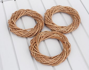 May include: Three natural woven wicker wreaths of varying sizes. The wreaths are made of brown, natural wicker and are arranged on a white surface.