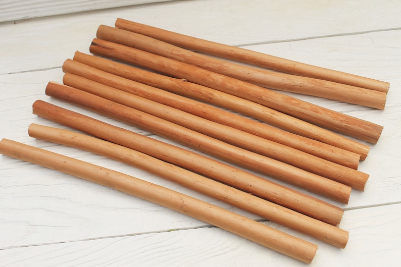 Peut inclure: Un groupe de 12 b&acirc;tonnets de cannelle naturelle, dispos&eacute;s en &eacute;ventail sur une surface en bois blanc. Les b&acirc;tonnets sont bruns et ont une texture rugueuse.