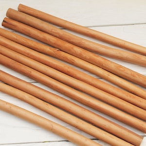 Peut inclure: Un ensemble de b&acirc;tonnets de cannelle naturelle, dispos&eacute;s en &eacute;ventail sur une surface en bois blanc. Les b&acirc;tonnets sont de diff&eacute;rentes longueurs et ont une couleur brun clair.