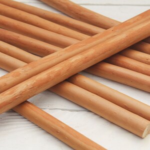 Peut inclure: Un groupe de chevilles en bois brun naturel, dispos&eacute;es en croisillon sur une surface blanche.