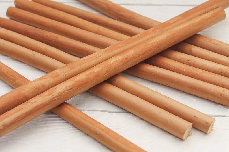 Peut inclure: Un groupe de chevilles en bois brun naturel, dispos&eacute;es en croisillon sur une surface blanche.