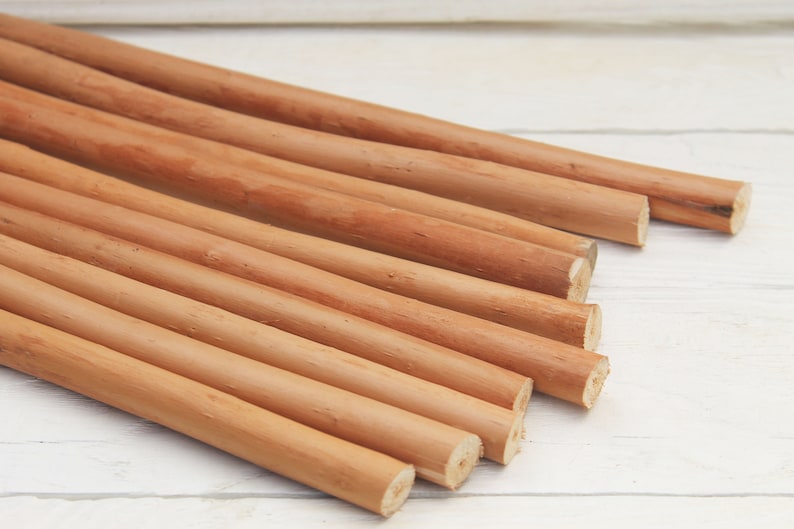 Peut inclure: Un groupe de 10 chevilles en bois lisses de couleur brun clair, dispos&eacute;es en &eacute;ventail sur une surface en bois blanc.
