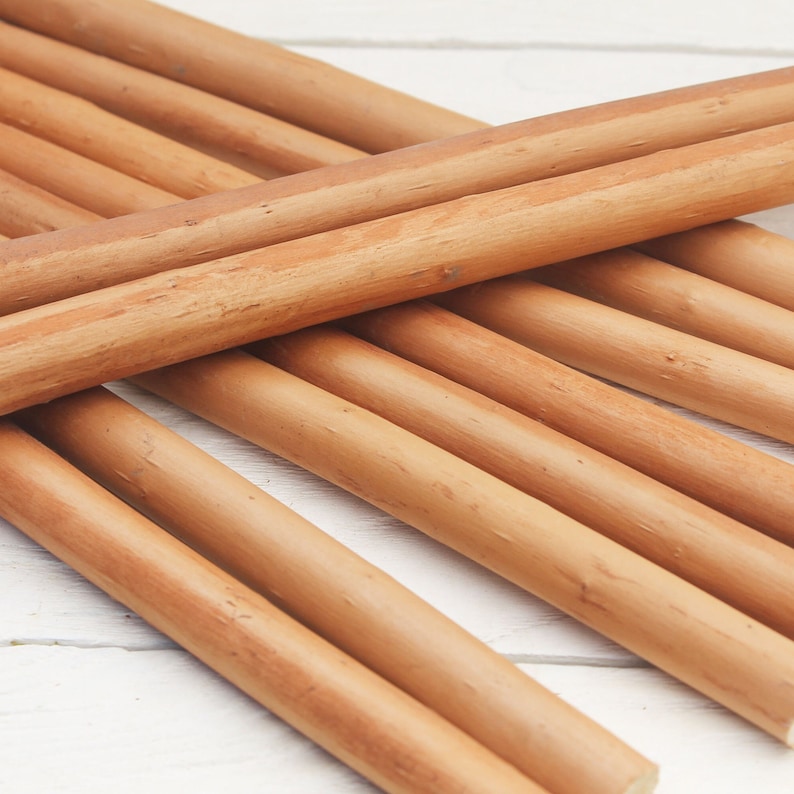 Peut inclure: Gros plan sur un faisceau de chevilles en bois lisses de couleur brun clair. Les chevilles sont dispos&eacute;es en croisillon, mettant en valeur leur grain de bois naturel.