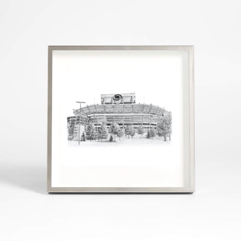 May include: A black and white framed print of a football stadium. The stadium is drawn in a realistic style and features a large scoreboard with a logo.