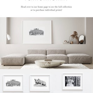 May include: A collection of black and white illustrations of Penn State landmarks and imagery, including Beaver Stadium, the Nittany Lion statue, Old Main, and the Bryce Jordan Center. The illustrations are framed and displayed on a white wall in a modern living room setting.
