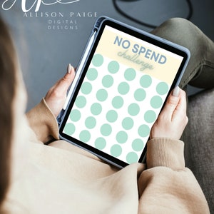 May include: A digital tablet with a white background and a light blue polka dot pattern. The text "NO SPEND challenge" is written in white on a yellow background.