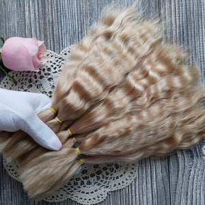 Peut inclure: Un paquet de m&egrave;ches de cheveux humains blonds clairs attach&eacute;es ensemble avec des &eacute;lastiques jaunes. Les cheveux sont ondul&eacute;s et semblent &ecirc;tre en bon &eacute;tat.
