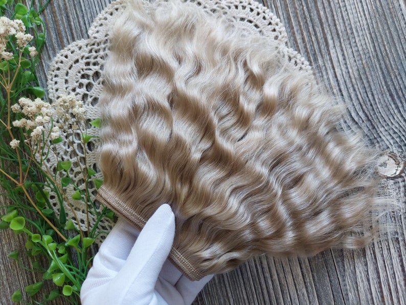Puede incluir: Un paquete de pelo de mu&ntilde;eca ondulado, rubio claro. El pelo est&aacute; en dos tramas y est&aacute; listo para ser cosido en la cabeza de una mu&ntilde;eca.