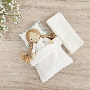 Handmade cloth doll in bed with miniature pillow and blanket, dollhouse bedding set