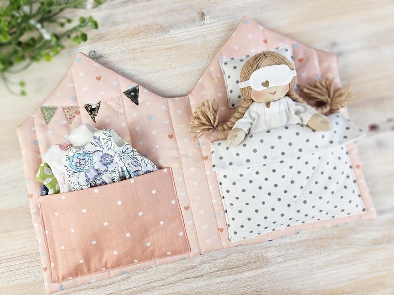 Opened fabric dollhouse interior, doll bedding and pockets for doll outfits, sewing pattern example