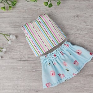 Striped doll top and blue floral skirt laid flat showing sewing details and pattern design