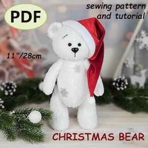 May include: A white plush Christmas bear wearing a red and white Santa hat. The bear has silver snowflake accents and is 28 cm tall. The image includes the text "PDF", "sewing pattern and tutorial", and "CHRISTMAS BEAR".